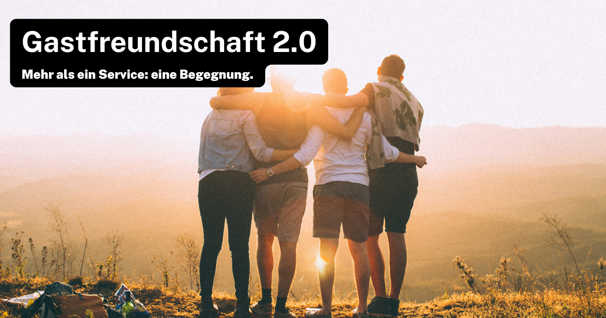 Vier Personen stehen auf einem Hügel und umarmen sich, während sie in den Sonnenuntergang blicken. Der Text „Gastfreundschaft 2.0“ und „Mehr als ein Service: eine Begegnung.“ ist oben links im Bild zu sehen.