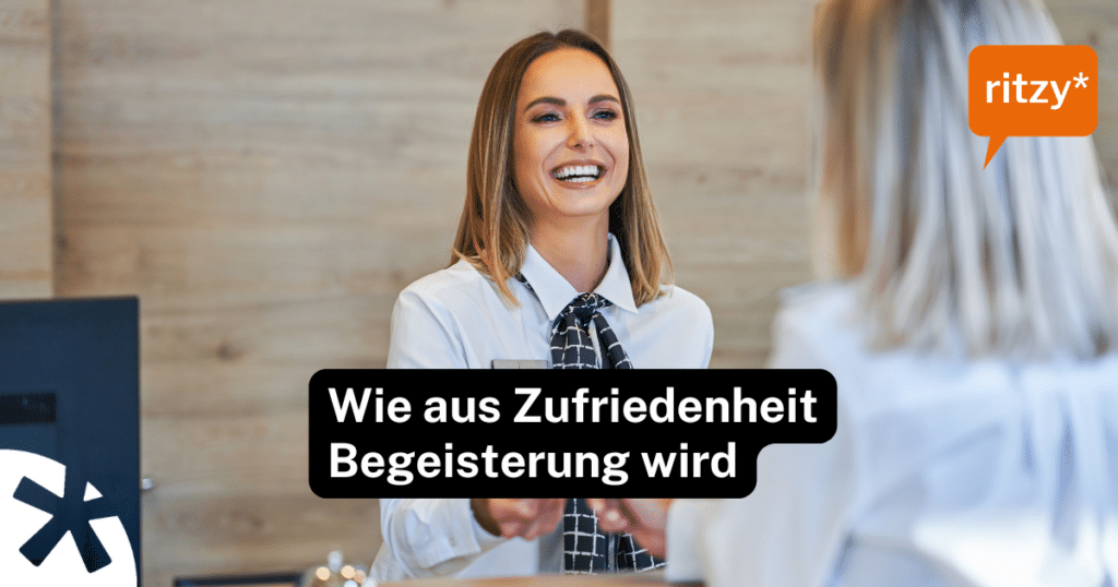 Hotelmitarbeitende begrüssen einen Gast an der Rezeption mit einem warmen, aufmerksamen Lächeln – Symbolbild für begeisternde Servicequalität.