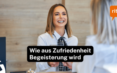 Hotelmitarbeitende begrüssen einen Gast an der Rezeption mit einem warmen, aufmerksamen Lächeln – Symbolbild für begeisternde Servicequalität.