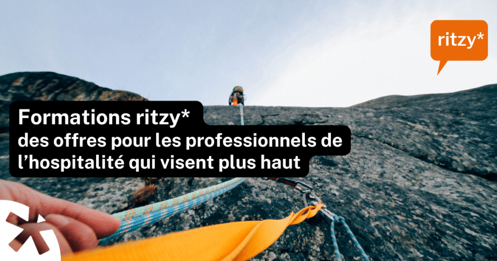 Corde d’escalade en première personne menant vers une personne en hauteur sur une paroi rocheuse, avec le texte « Formations ritzy* – des offres pour les professionnels de l’hospitalité qui visent plus haut » et le logo ritzy* en haut à droite.