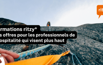 Corde d’escalade en première personne menant vers une personne en hauteur sur une paroi rocheuse, avec le texte « Formations ritzy* – des offres pour les professionnels de l’hospitalité qui visent plus haut » et le logo ritzy* en haut à droite.