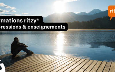 Personne assise sur un ponton en bois au bord d’un lac de montagne, face au soleil levant, avec le texte « Formations ritzy* – Impressions & enseignements » et le logo ritzy* en haut à droite.